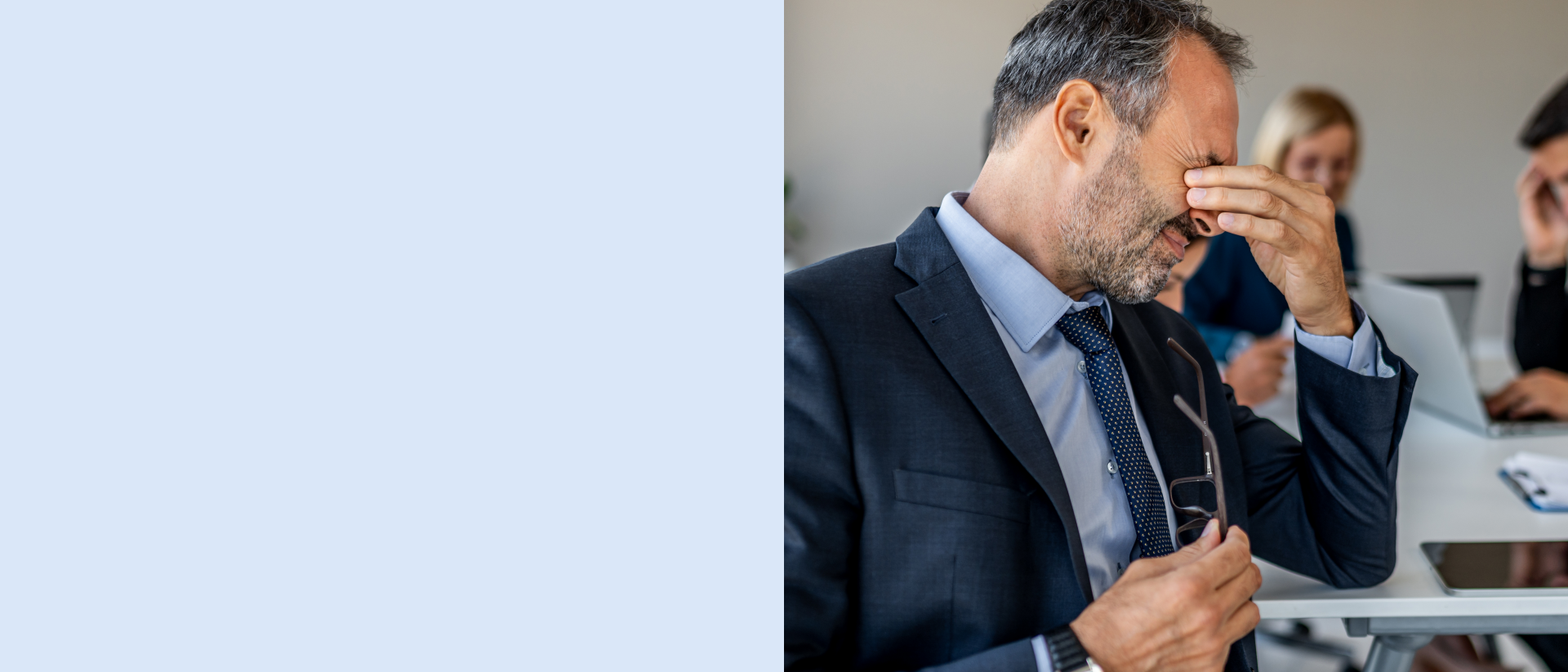 Ein Geschäftstreffen mit mehreren Personen in formeller Kleidung, wobei eine Person eine Brille hält und Gespräche stattfinden.