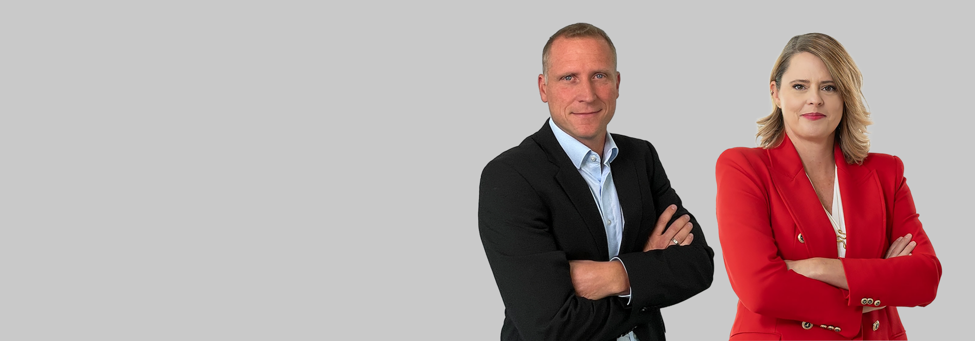 Das Bild zeigt zwei Personen, einen Mann in einem schwarzen Anzug und eine Frau in einem roten Blazer, die nebeneinander stehen und die Arme verschränkt haben. Die Gesichter sind unkenntlich gemacht.