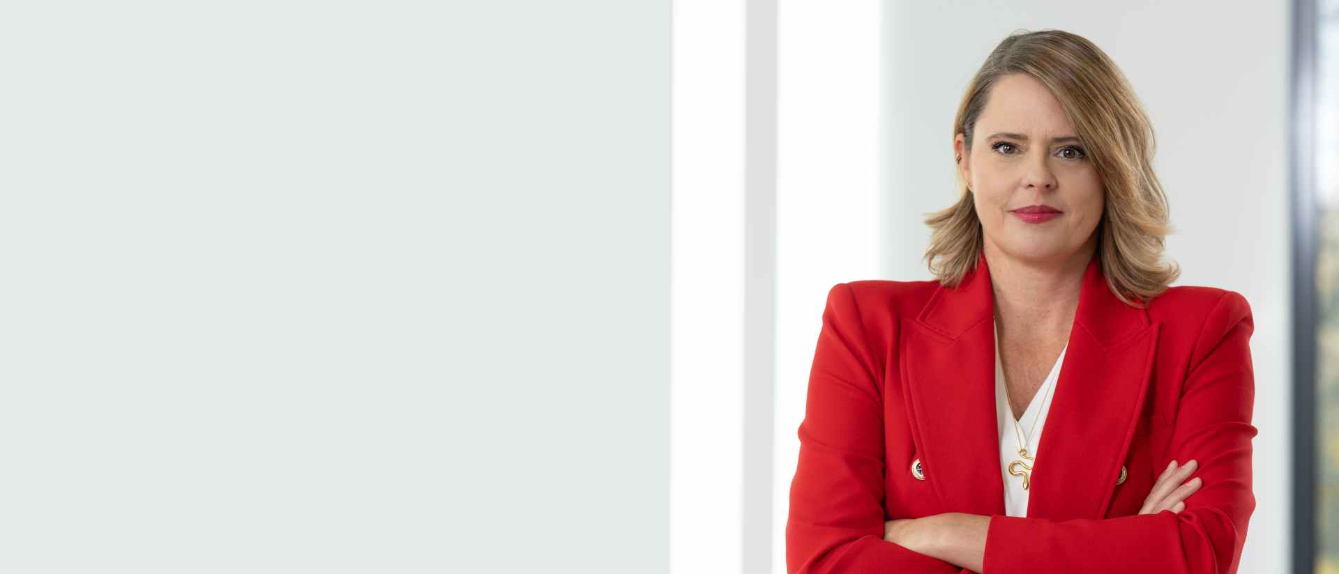 Die Person trägt ein rotes Jackett über einem weißen Hemd und ist möglicherweise in einem professionellen Umfeld. Der Hintergrund ist größtenteils unscharf oder neutral gehalten, was darauf hinweist, dass das Foto auf die Person fokussiert ist.